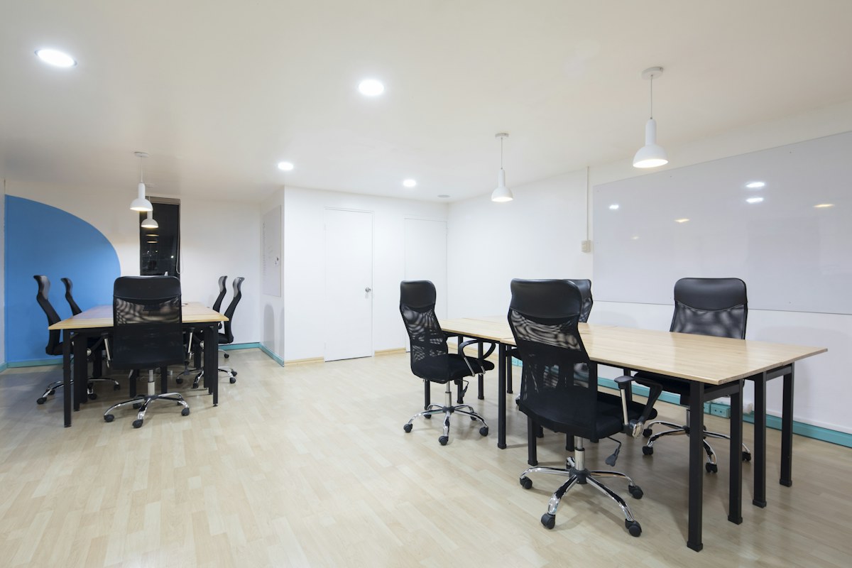 Bright office with clear desks, meeting tables and wood flooring